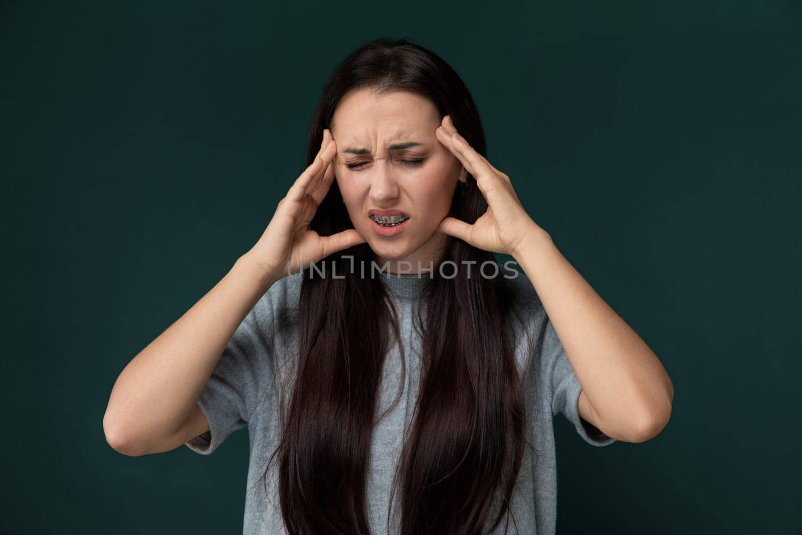 A woman is shown holding her head with both hands, displaying signs of distress or overwhelming emotion. Her facial expression conveys inner turmoil or a moment of intense stress.