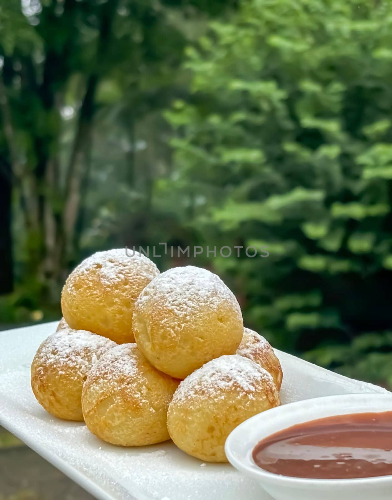 Homemade delicious sweet Dutch poffertjes mini pancakes with icing powdered sugar and chocolate fillings with additional chocolate sauce for cooking multimedia content creation