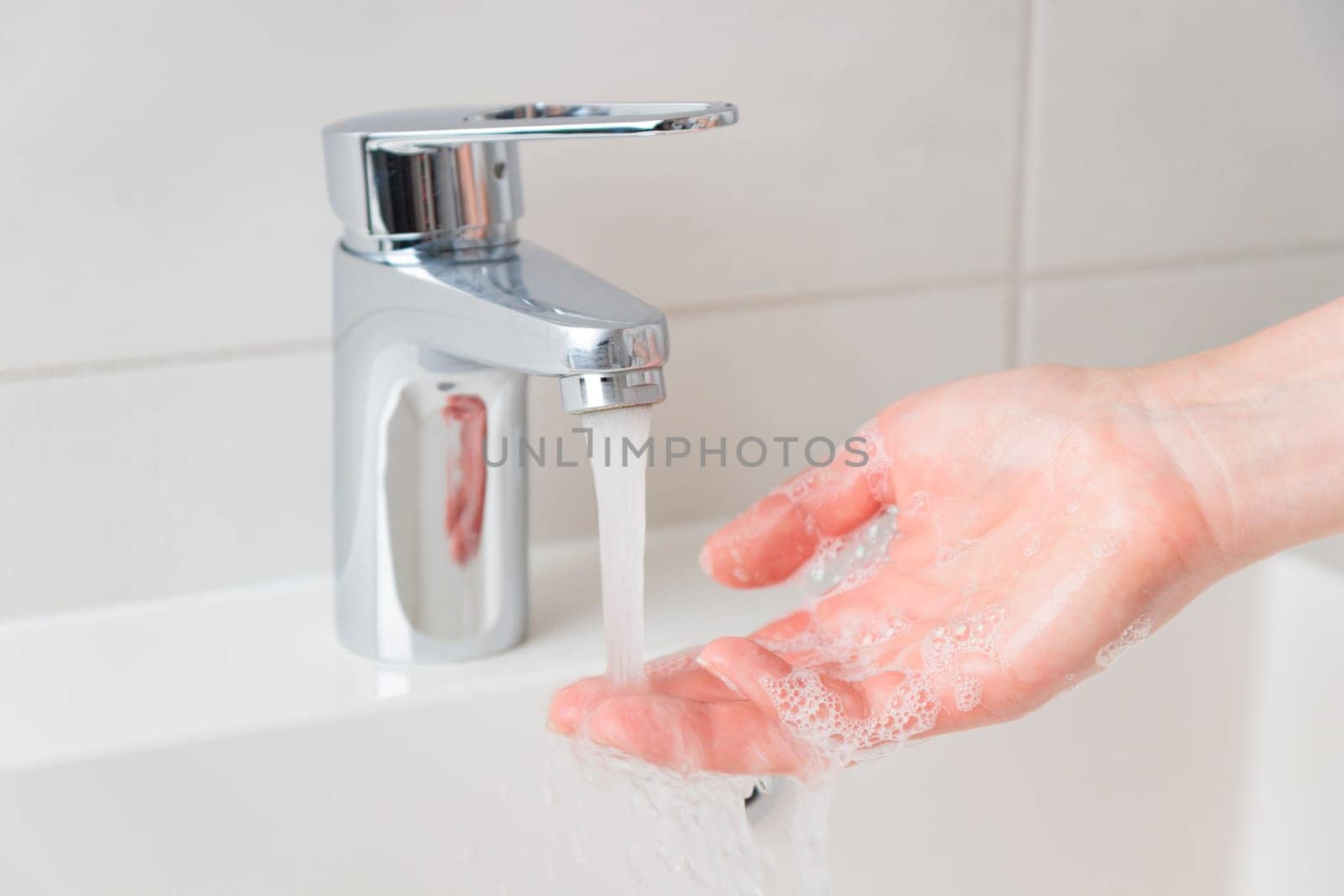 Banner of woman's soapy hands with running water in sink, cleaning skin care concept, white minimalistic bathroom