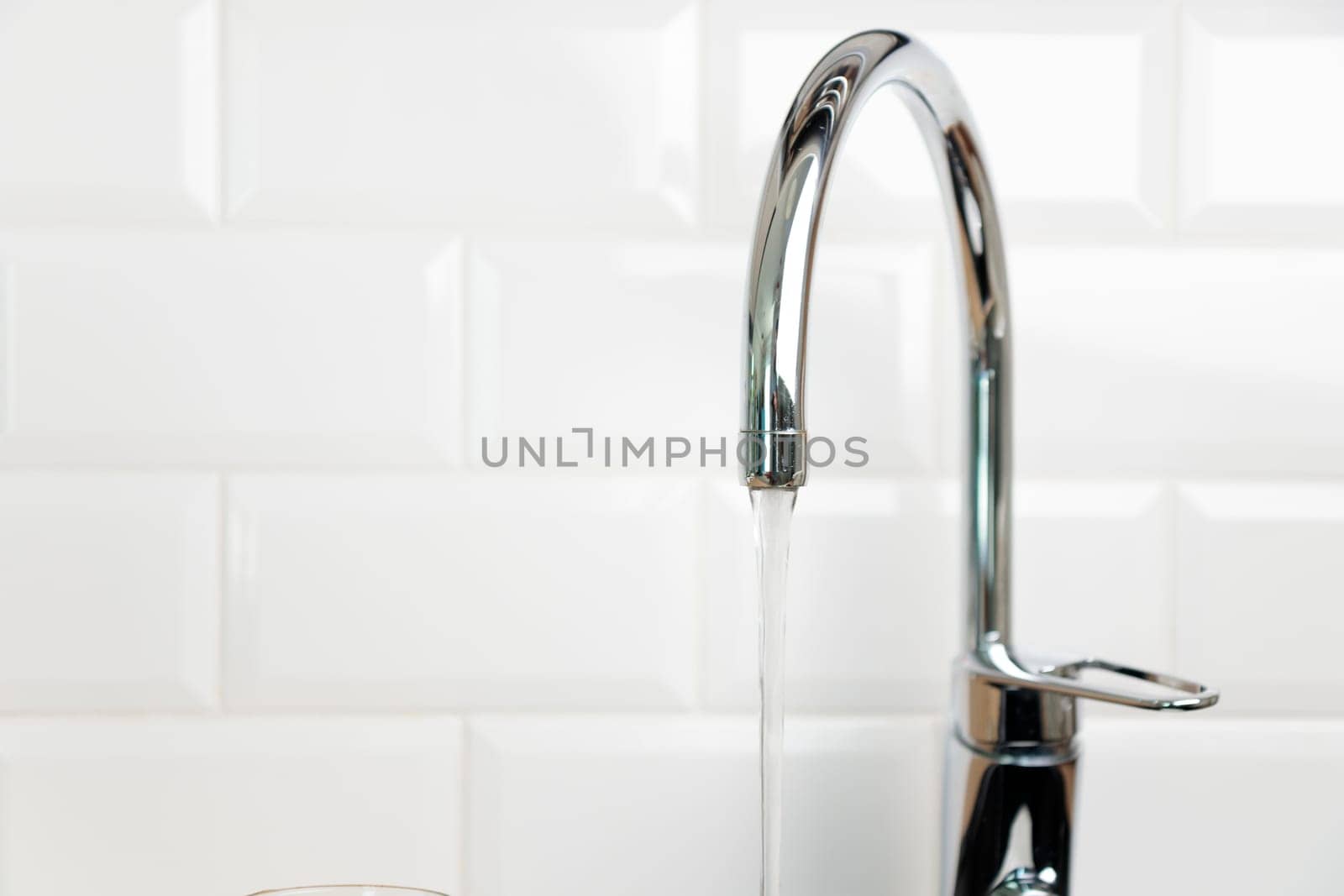 Modern kitchen chrome faucet, white tiles wall, tap with running water, pure water concept, saving natural recourses concept banner with copy space
