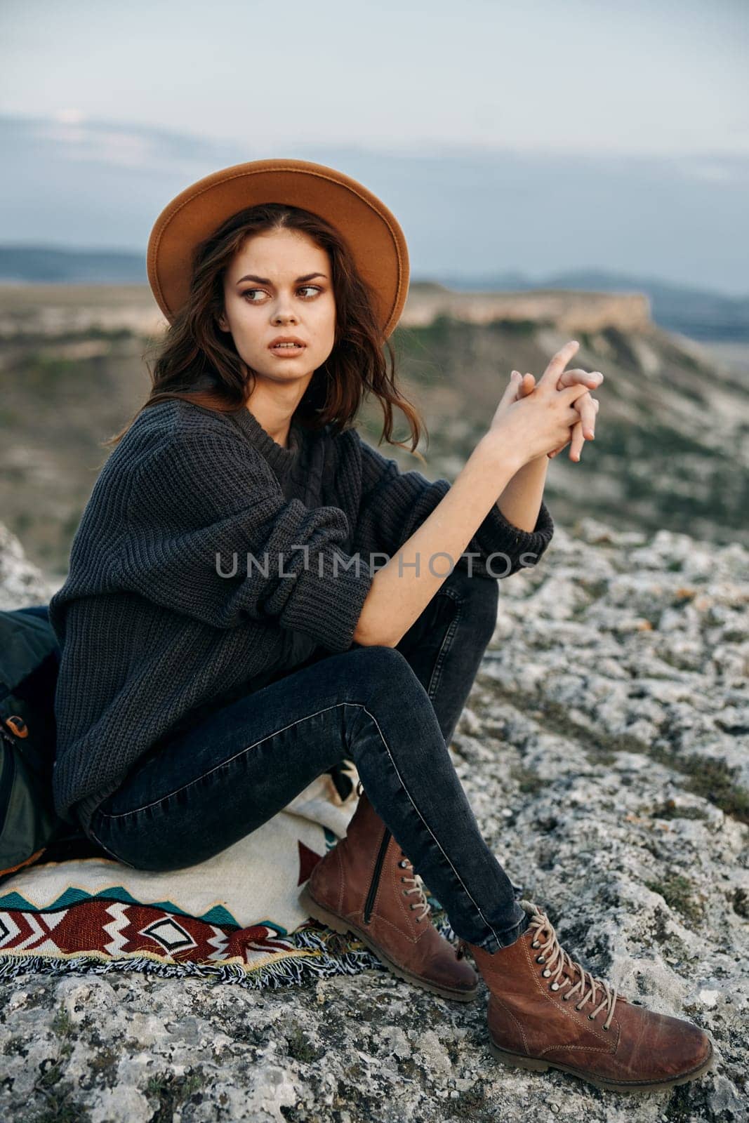 Serene moment woman in hat on mountaintop checking cell phone with picturesque view in background