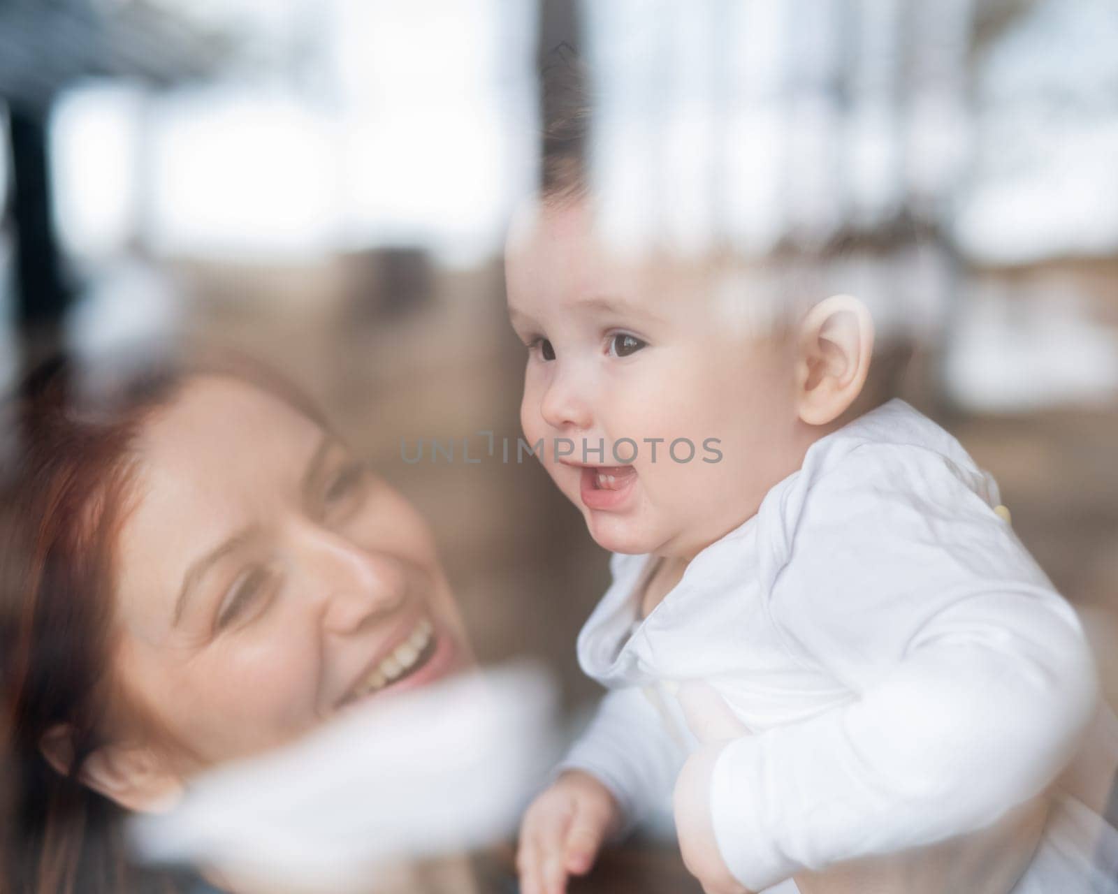 View through the window of a red-haired Caucasian woman holding her little son