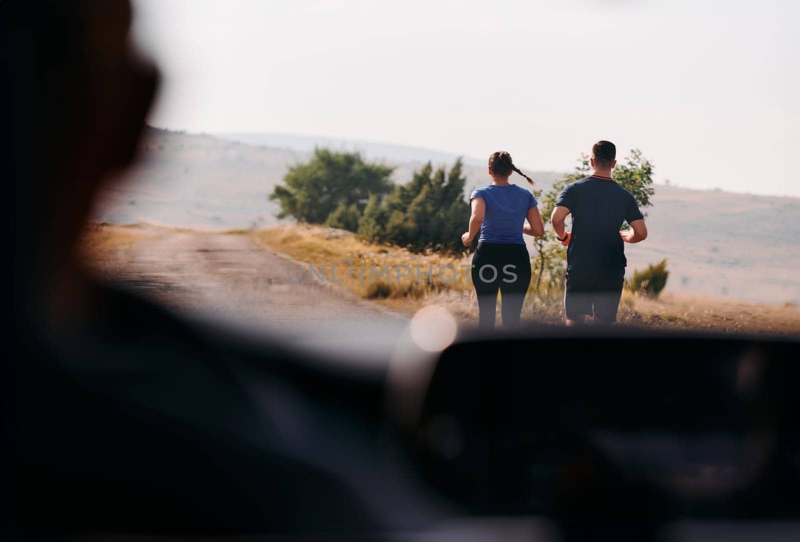 A romantic couple is captured running outdoors from the perspective of a car, embodying adventure and togetherness in their journey