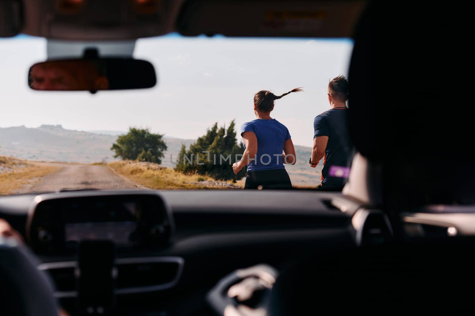 A romantic couple is captured running outdoors from the perspective of a car, embodying adventure and togetherness in their journey