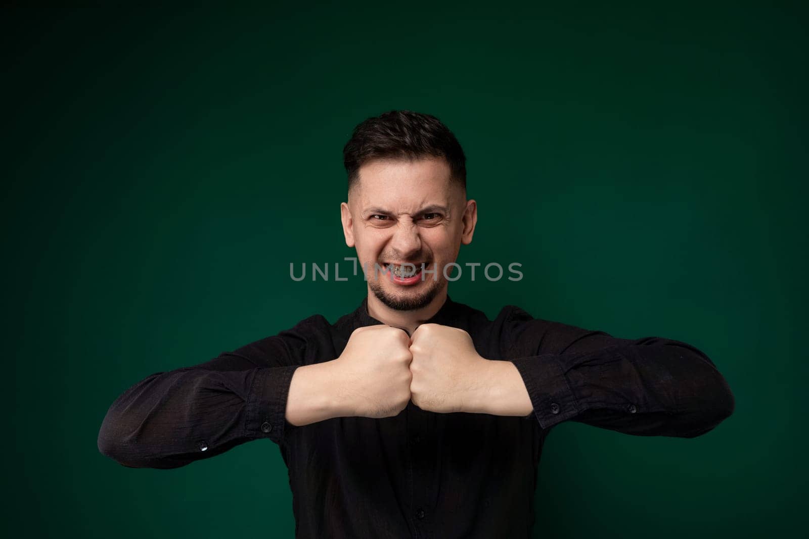 A man is shown with clenched fists, symbolizing determination or aggression. His hands are tightly closed in a symbolic gesture of strength or defiance.