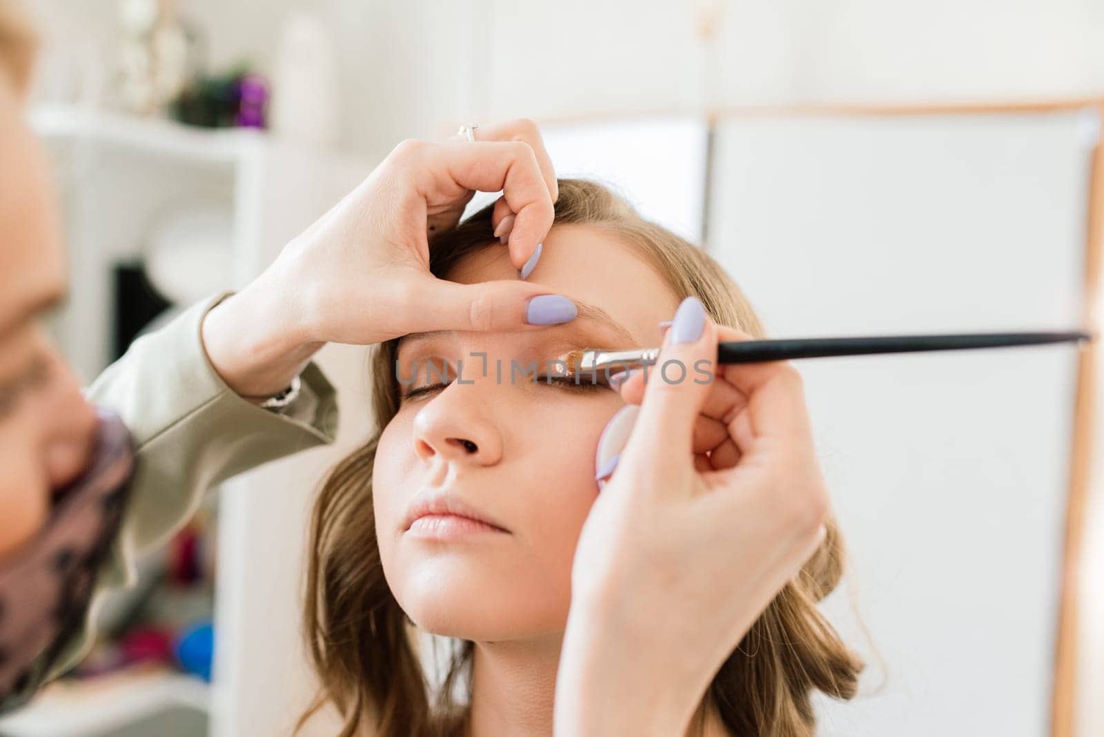 Woman make-up artist work in her studio with model by Zelenin