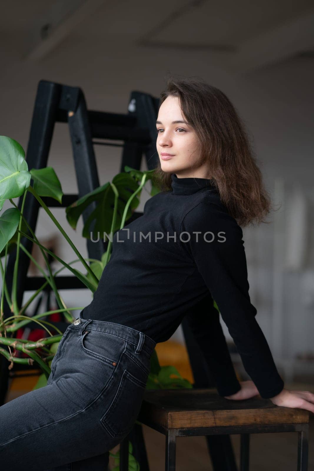 young beautiful woman posing in a black sweater near the window