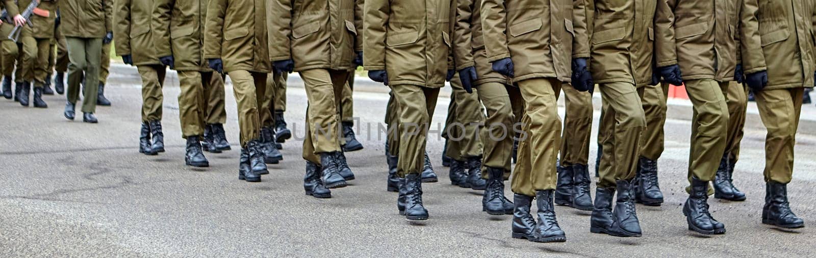 Disciplined soldiers in camouflage march in perfect synchronization during a military parade. Helmets and rifles add to the display of unity and strength, evoking pride.