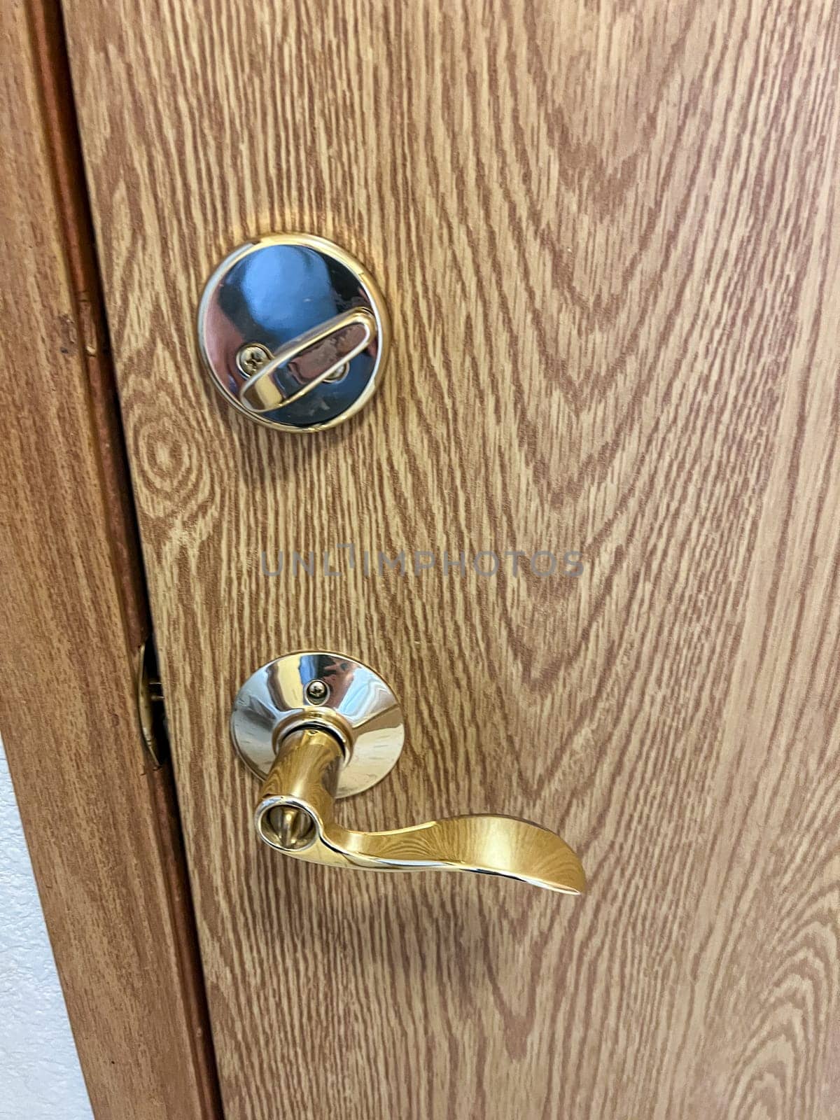 Denver, Colorado, USA-November 25, 2023-A close-up view of a polished brass door handle and matching deadbolt on a wooden door. The shiny brass fixtures add a touch of elegance and security to the doors natural wood grain.