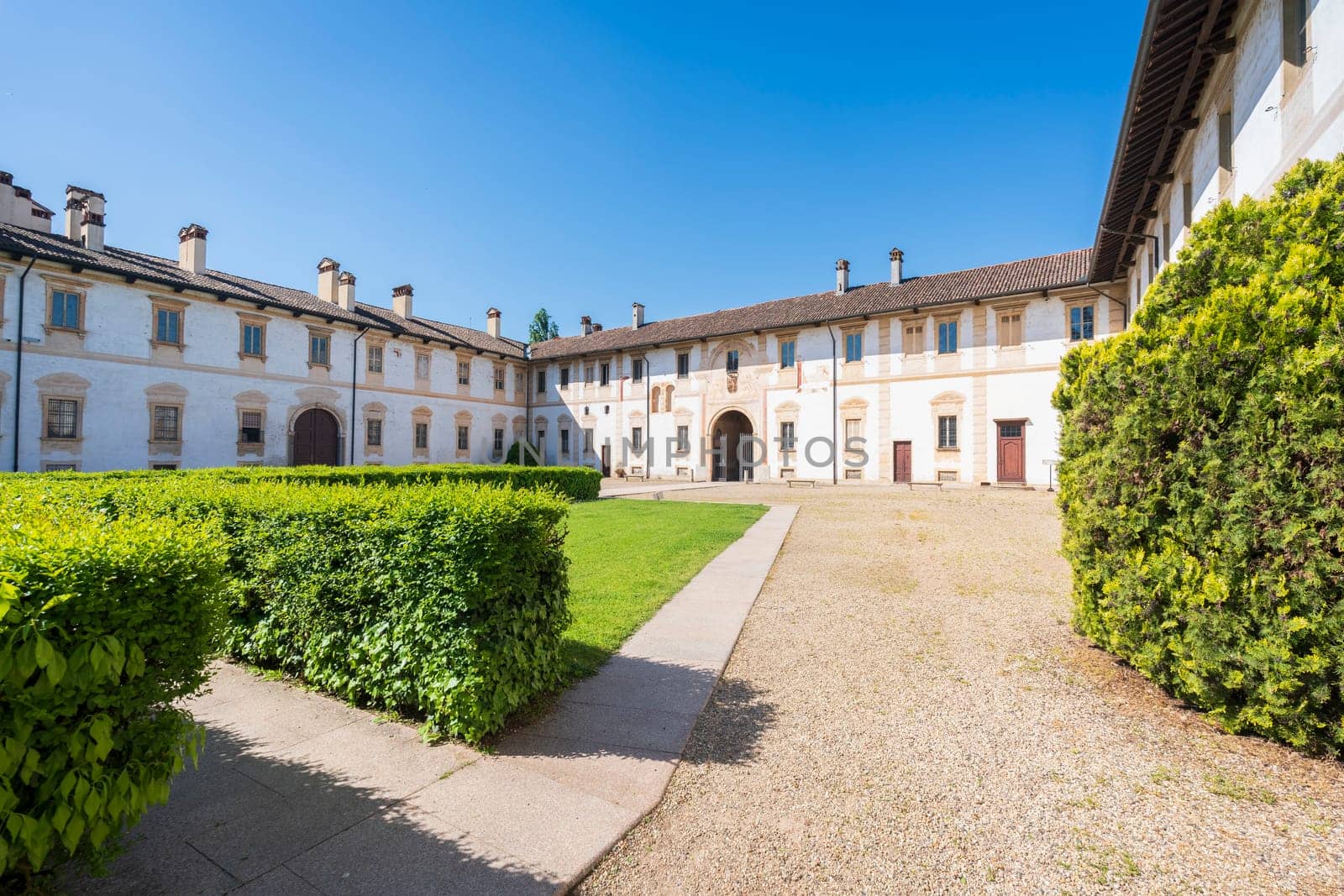 Certosa di Pavia monastery, historical monumental complex that includes a monastery and a sanctuary. green court and a church.The Ducale Palace on the right,Pavia,Italy.