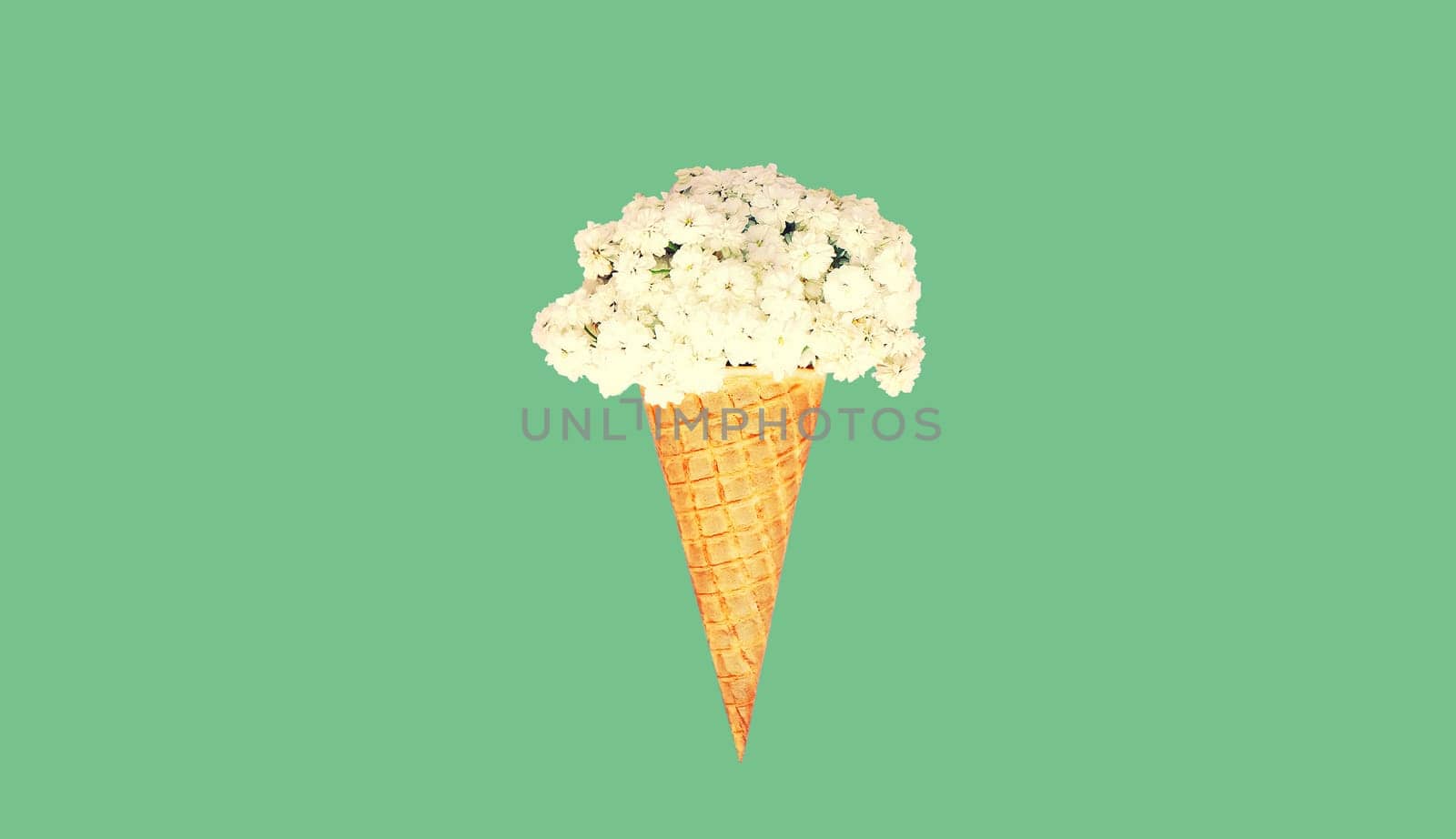 Stylish ice cream cone with flowers on green background, top view, flat lay