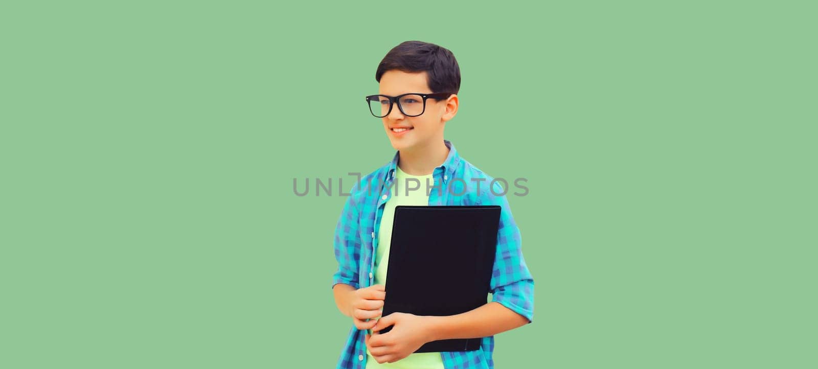 Happy smiling teenager boy in eyeglasses with folder or book on green background by Rohappy