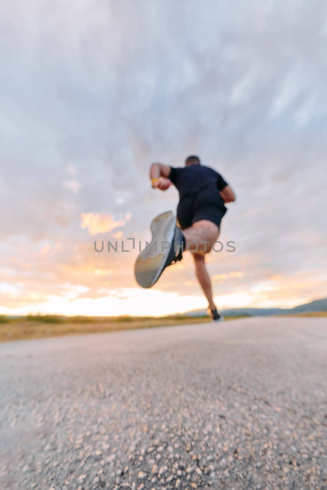 A breathtaking wide shot captures a determined man gracefully running against the backdrop of a vibrant sunset