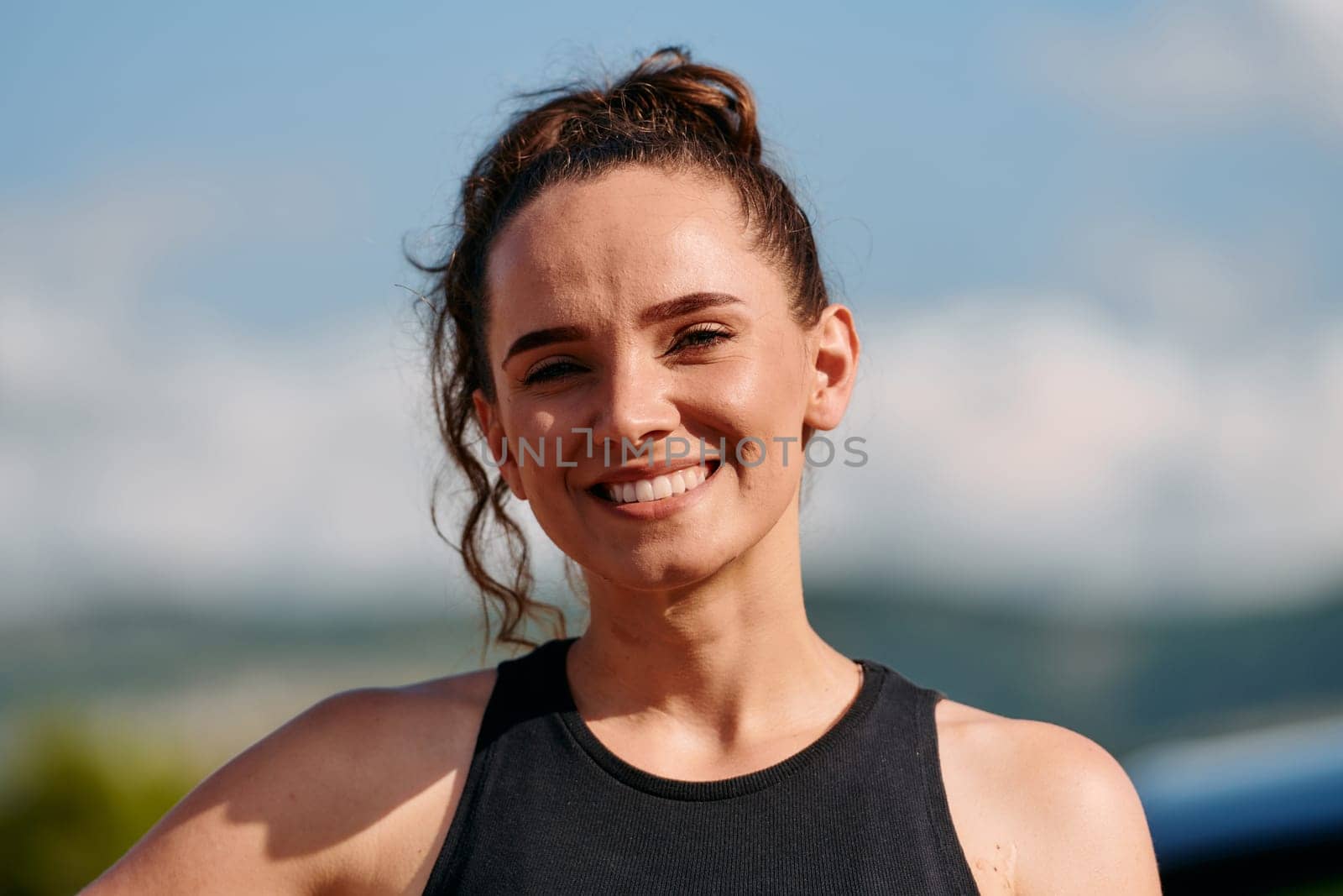In a captivating close up portrait, an athletic woman exudes confidence and happiness, her wide smile radiating infectious joy and positivity.