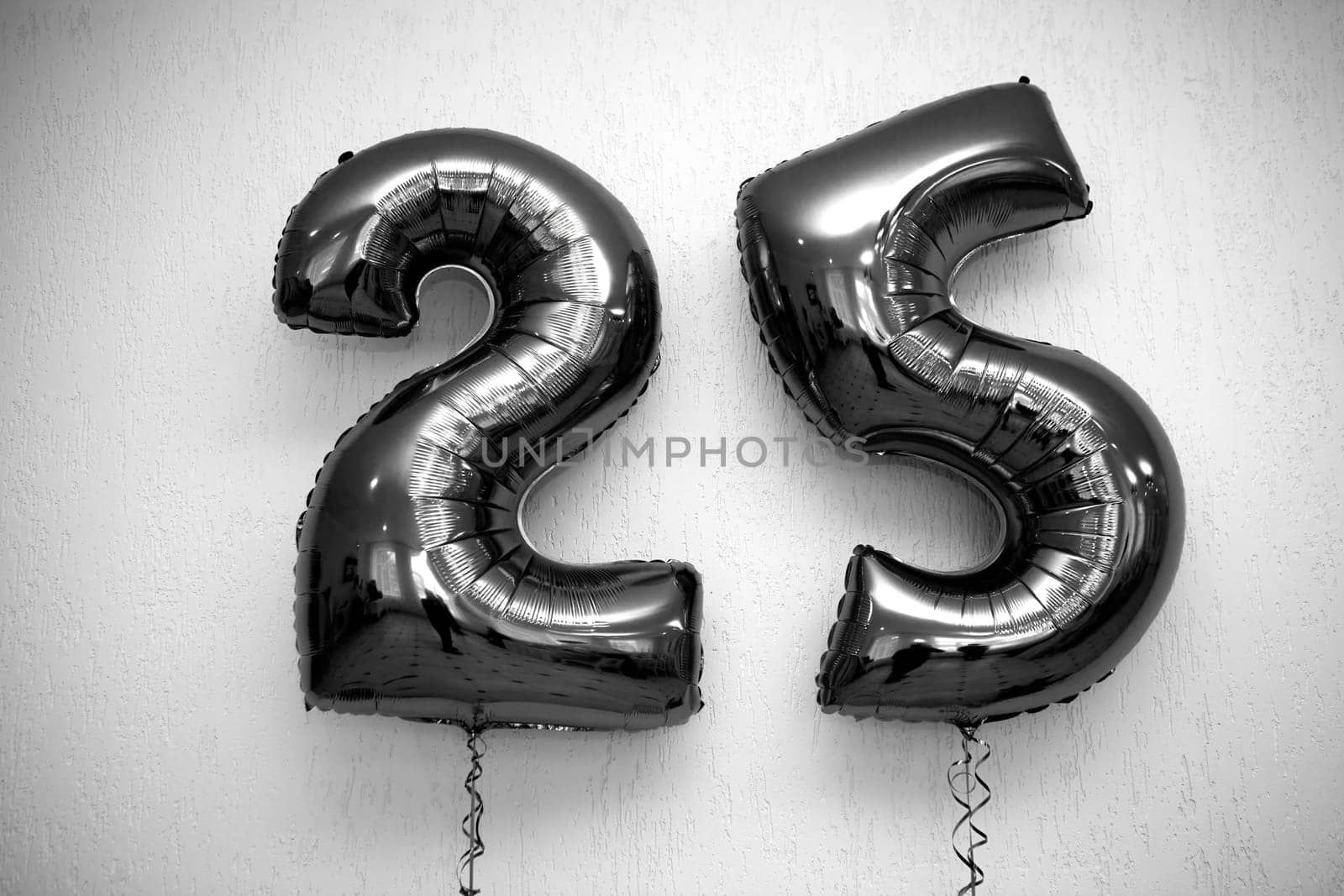Two stunning black shiny number 25 balloons on a solid white background, adding elegance to any birthday or anniversary celebration. Ideal for party decorations and festive occasions.