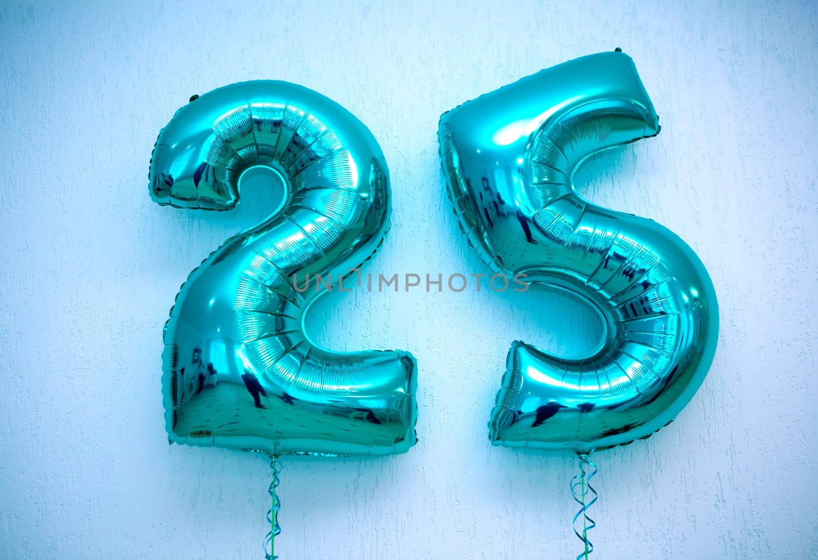 Close-up of blue number 25 foil balloons on white background with copy space. Ideal for birthdays and anniversaries. Numeral 25 inflatable balloon isolated on white.