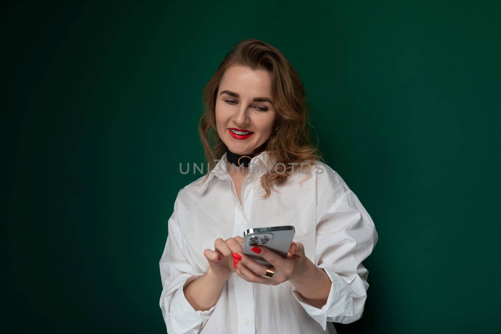 A woman wearing a white shirt is seen holding a cell phone in her hand.