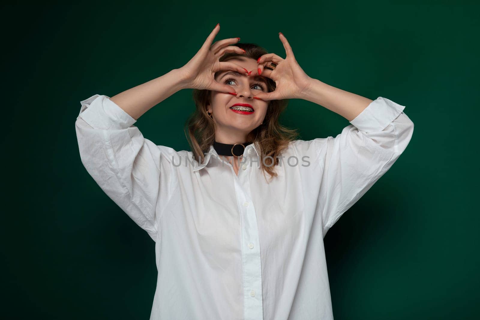 A woman standing with her hands raised up to her eyes, covering them partially or fully. She appears to be shielding her eyes or adjusting her vision.