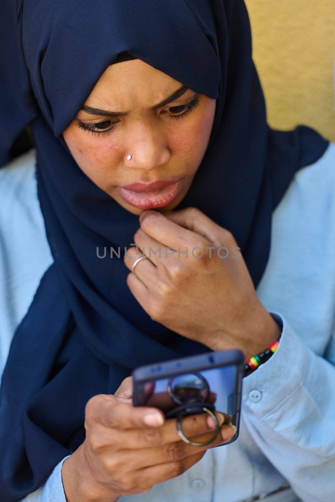 A close-up portrait captures the engagement of a Middle Eastern teenage Muslim girl in her digital world, as she uses a smartphone with focused attention
