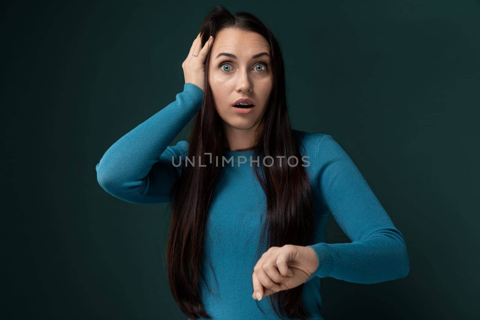 A woman wearing a blue shirt is seen holding her head in this candid shot. She appears distressed or in deep thought, possibly dealing with stress or a headache.