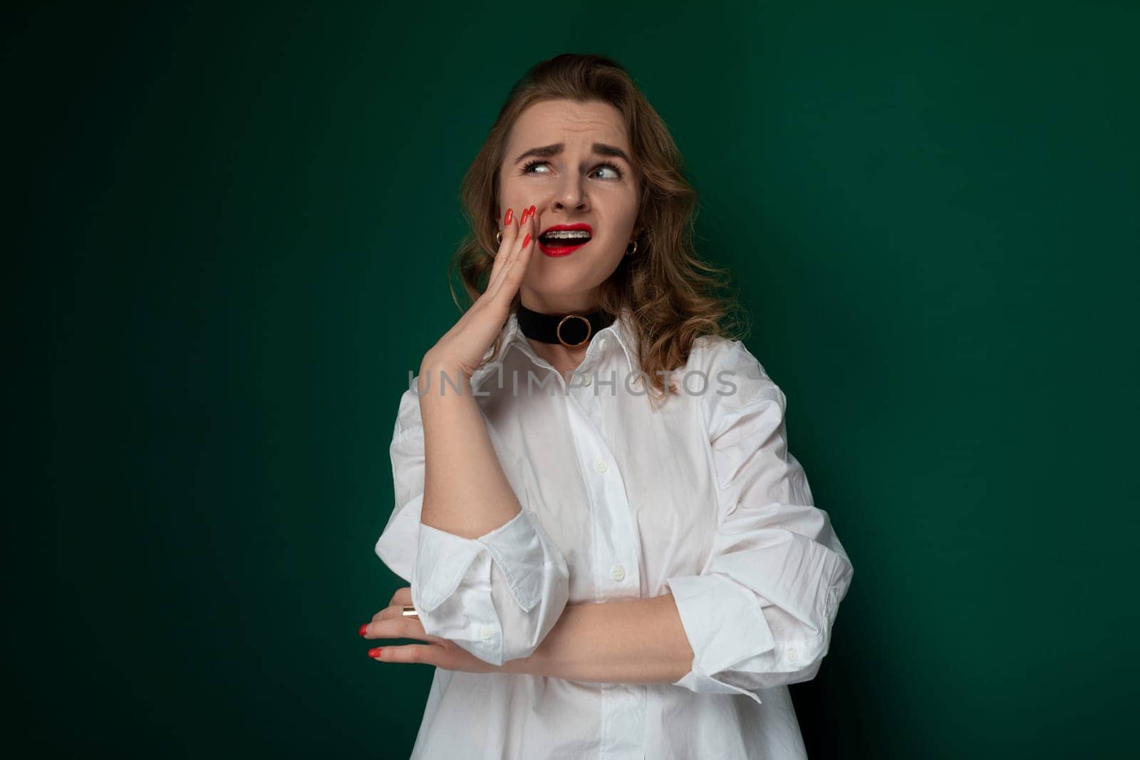 A woman wearing a white shirt is striking a pose for a photograph. She stands confidently, with a smile on her face, in front of a camera capturing her image.