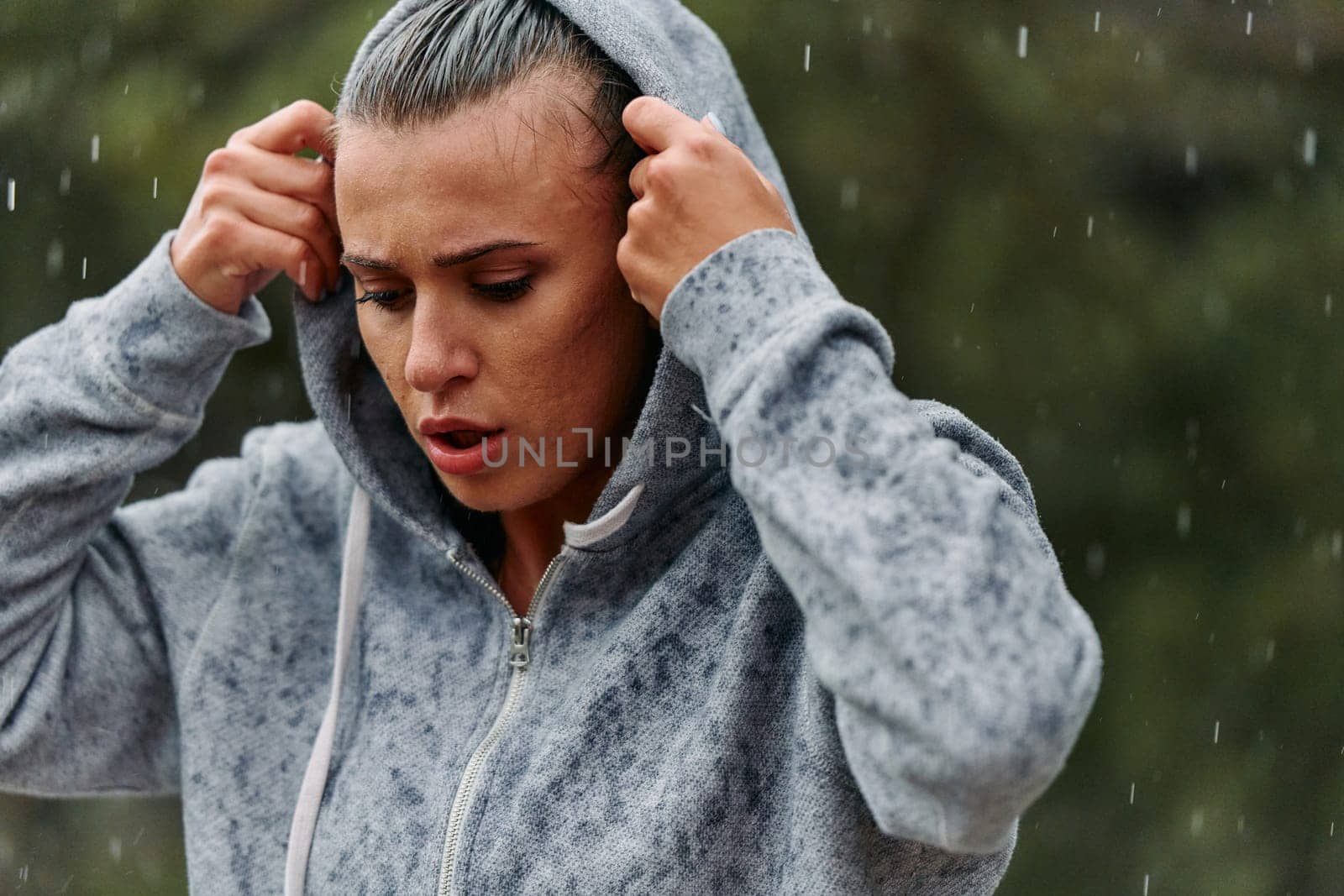 A determined woman finds solace in the rain as she rests after an intense run, embracing the rejuvenating rhythm of the falling raindrops