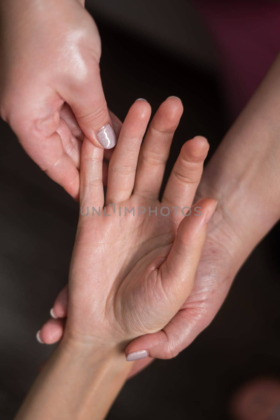 The masseuse massages the client's palms. Close-up of hands during a spa treatment. Vertical photo