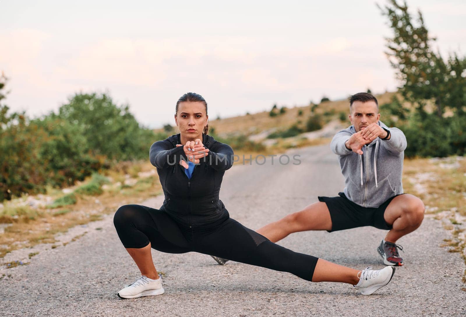 A romantic couple enjoys a moment of connection and relaxation as they stretch their bodies after an intense morning run.