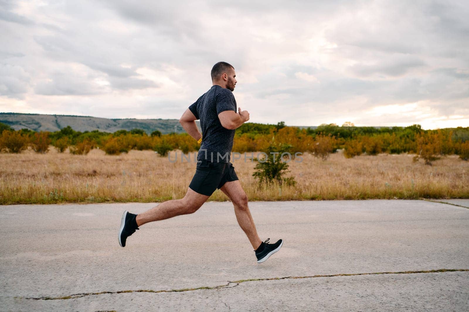 An athletic man jogs under the sun, conditioning his body for life's extreme challenges, exuding determination and strength in his preparation for the journey ahead