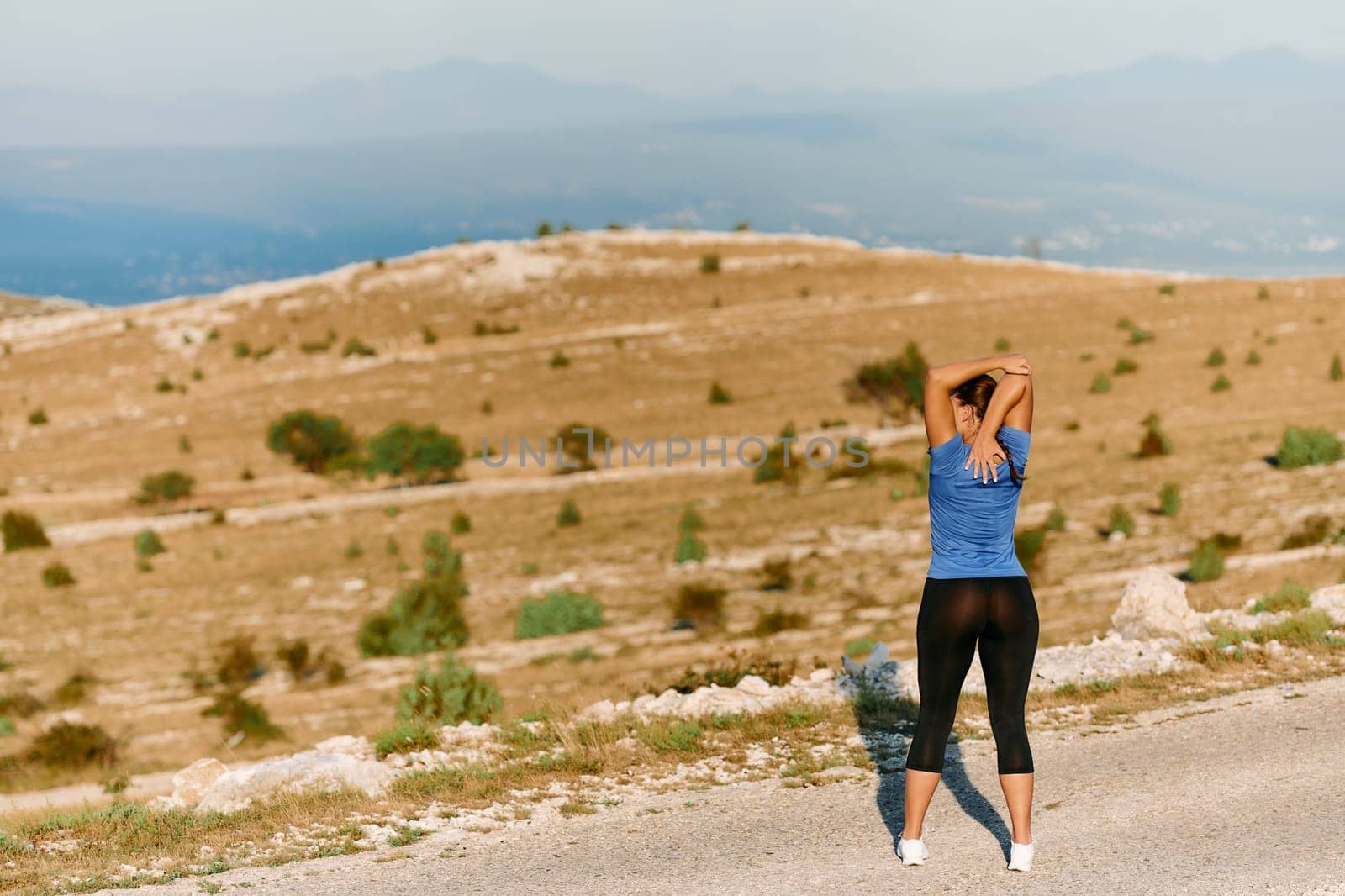 Determined Female Athlete Stretching After an Intense Run Through Rugged Mountain Terrain. by dotshock