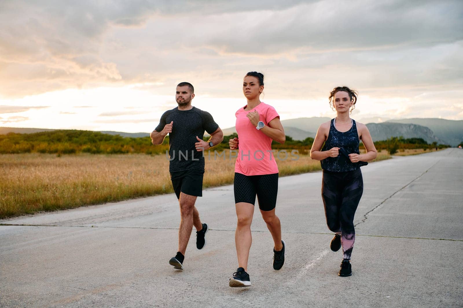 In a breathtaking scene of nature's beauty, an athlete leads a group run at sunset, inspiring and motivating her companions with her leadership and determination