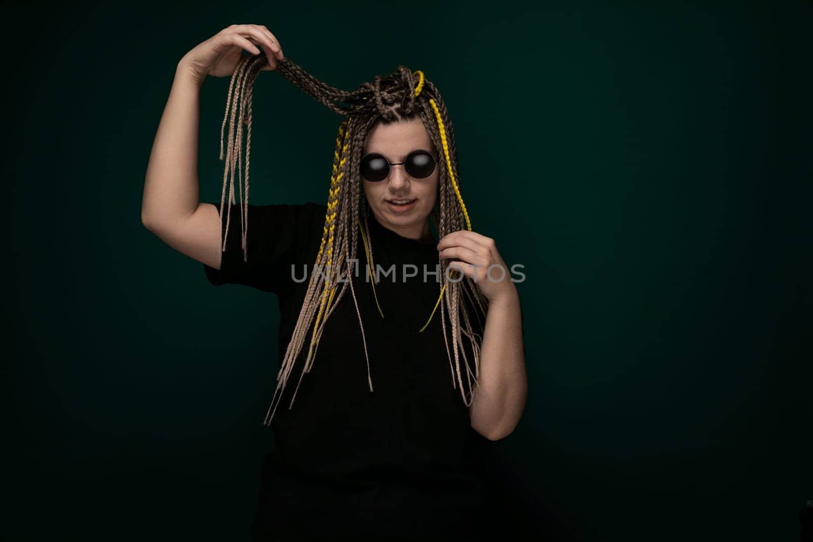 A woman with dreadlocks styled in a black shirt poses for the camera, showcasing her unique hairstyle and fashion sense.