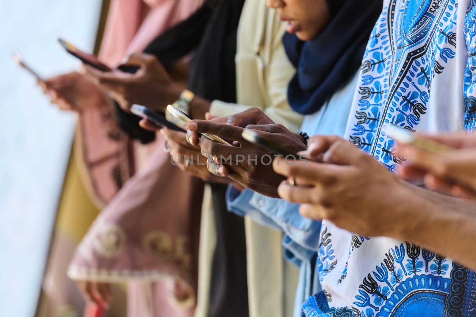 A diverse group of teenagers standing together against a wall, engrossed in their smartphones, showcasing modern connectivity and social interaction.