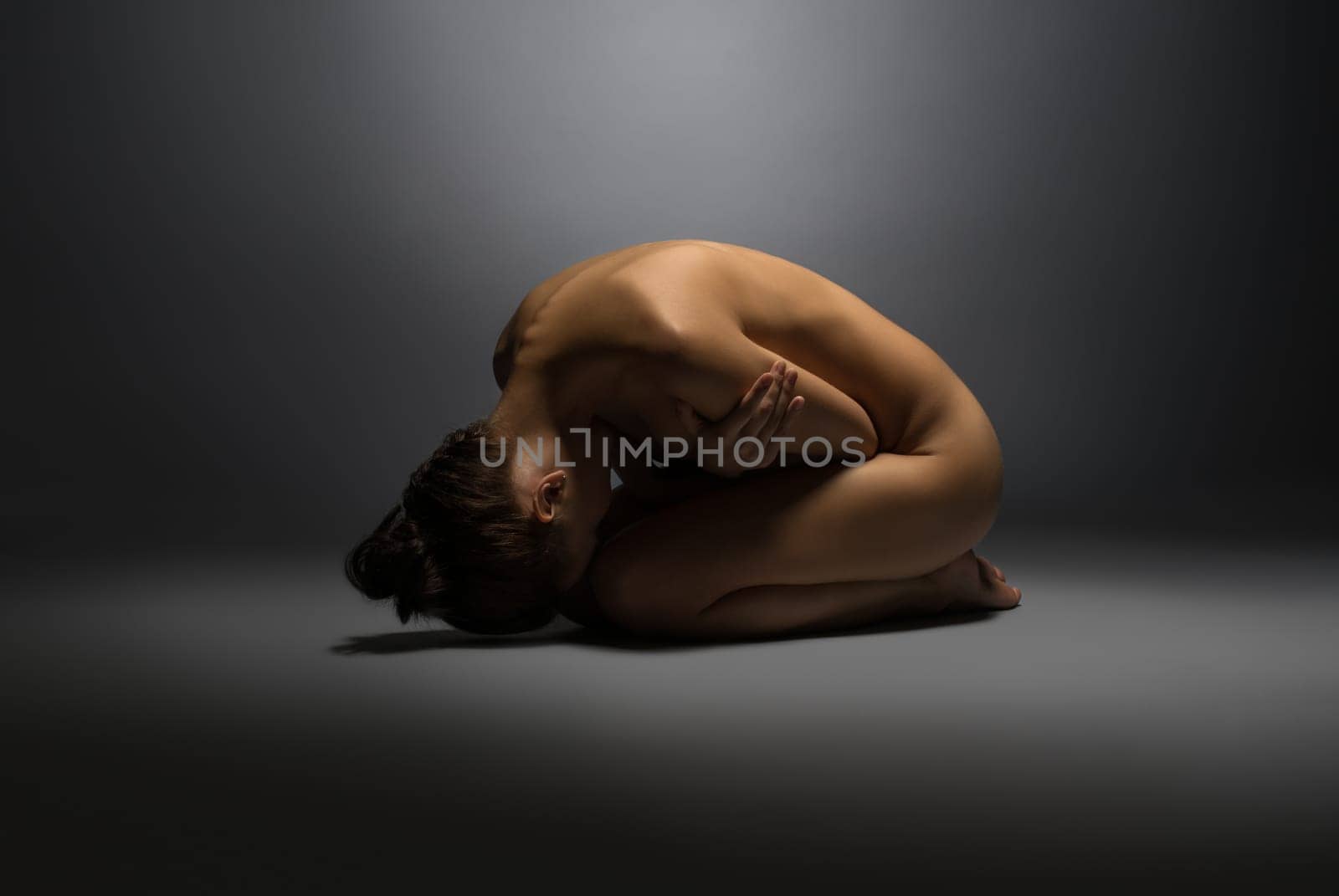 Concept of vulnerability. Naked woman lying on floor, hugging herself