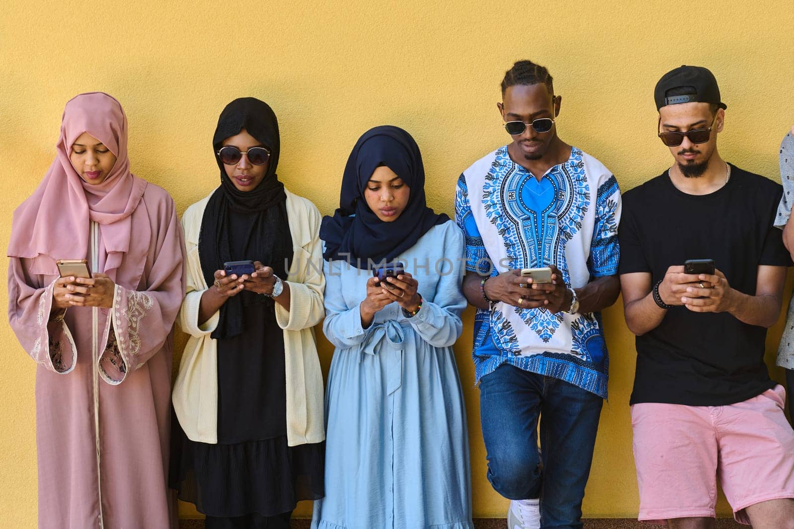 Diverse Teen Group Standing Together Against Wall Using Smartphones by dotshock