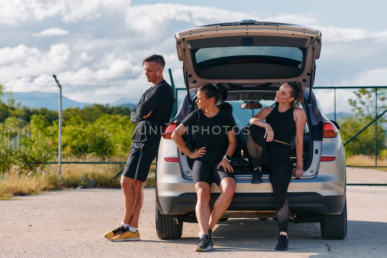 A unified team of athletes stands ready next to a car, symbolizing camaraderie and preparation for the challenges ahead.