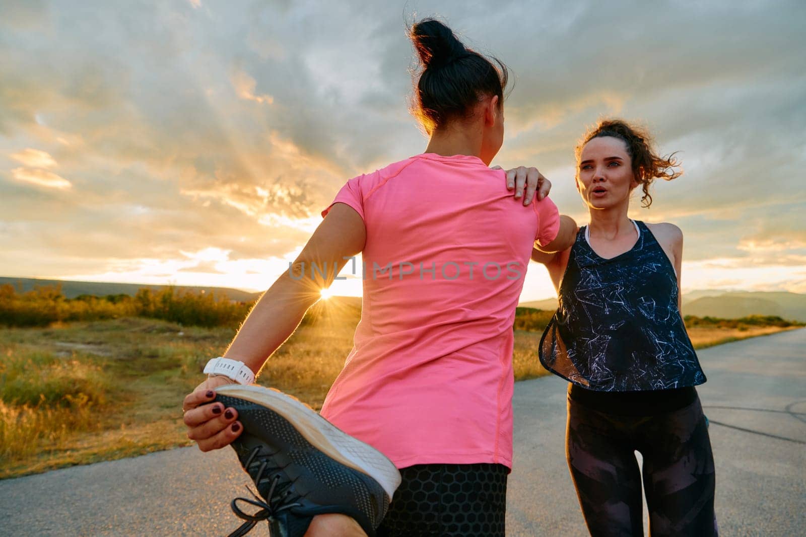 Two women athletes are seen stretching after an intense run, epitomizing dedication to fitness and appreciation for nature's beauty.