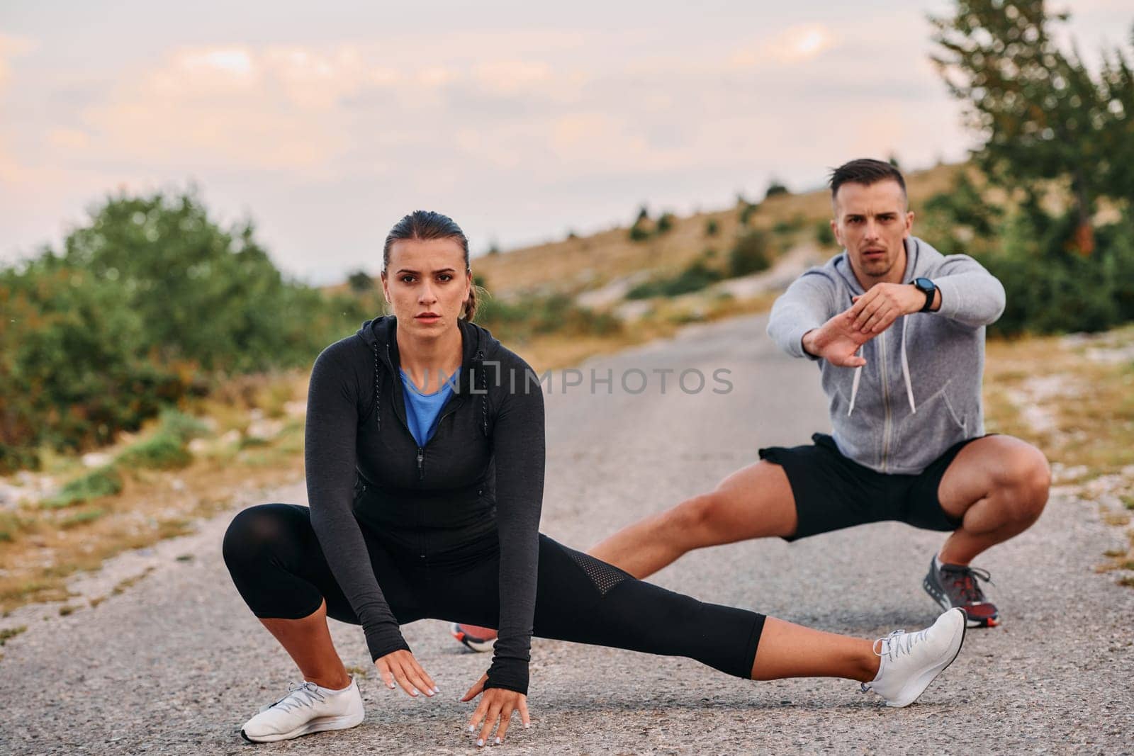 A romantic couple enjoys a moment of connection and relaxation as they stretch their bodies after an intense morning run.