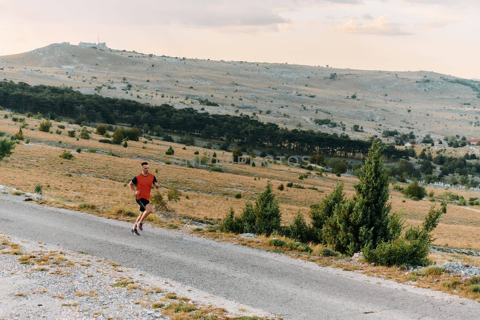 Determined Athlete Running Through Rugged Mountain Terrain at Sunrise. by dotshock