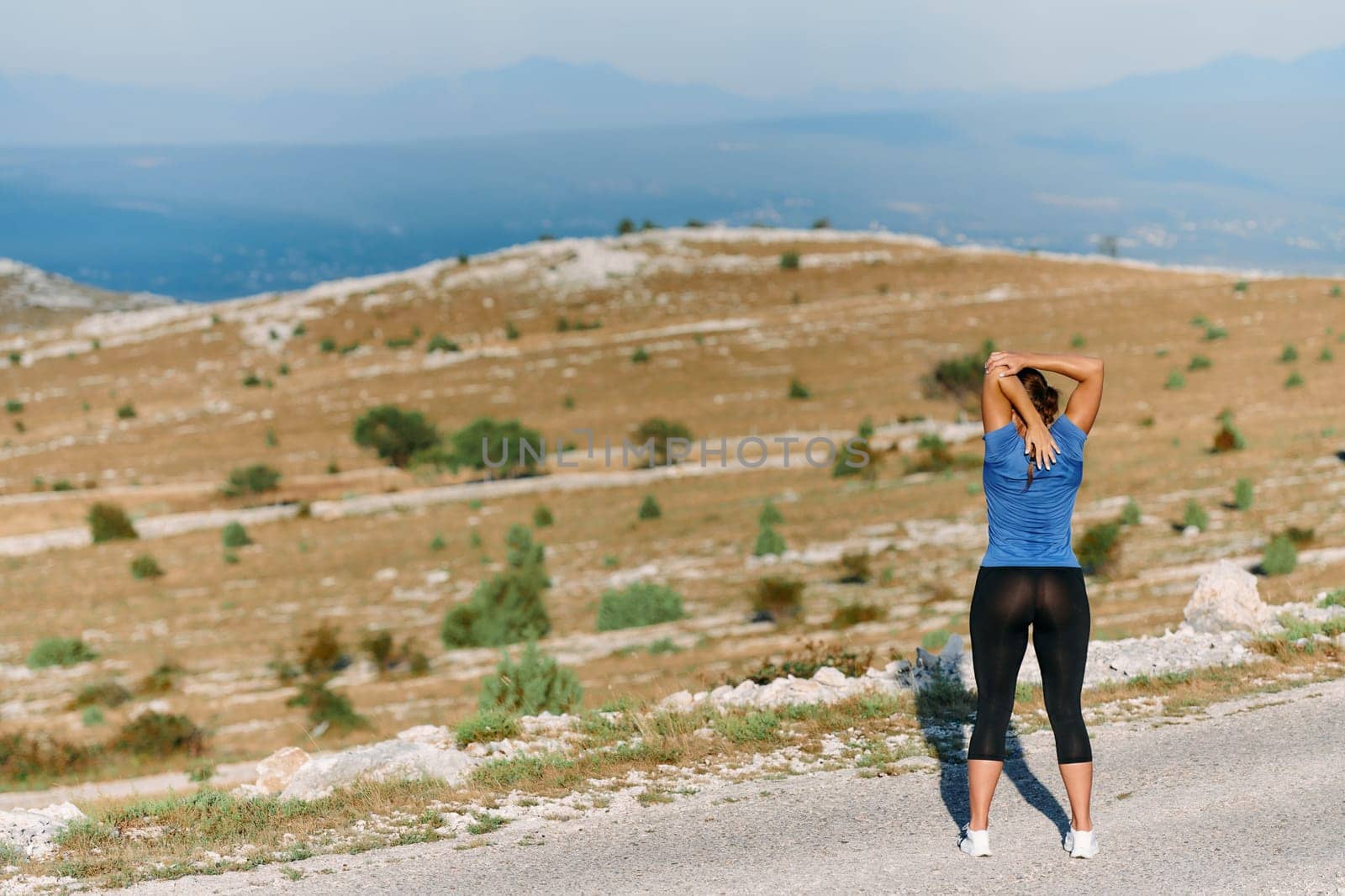 Determined Female Athlete Stretching After an Intense Run Through Rugged Mountain Terrain. by dotshock