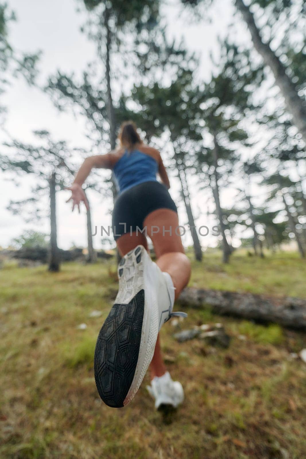 A brave woman traverses through the forest, fearlessly leaping over dangerous obstacles with determination and agility, showcasing her adventurous spirit and athletic prowess.