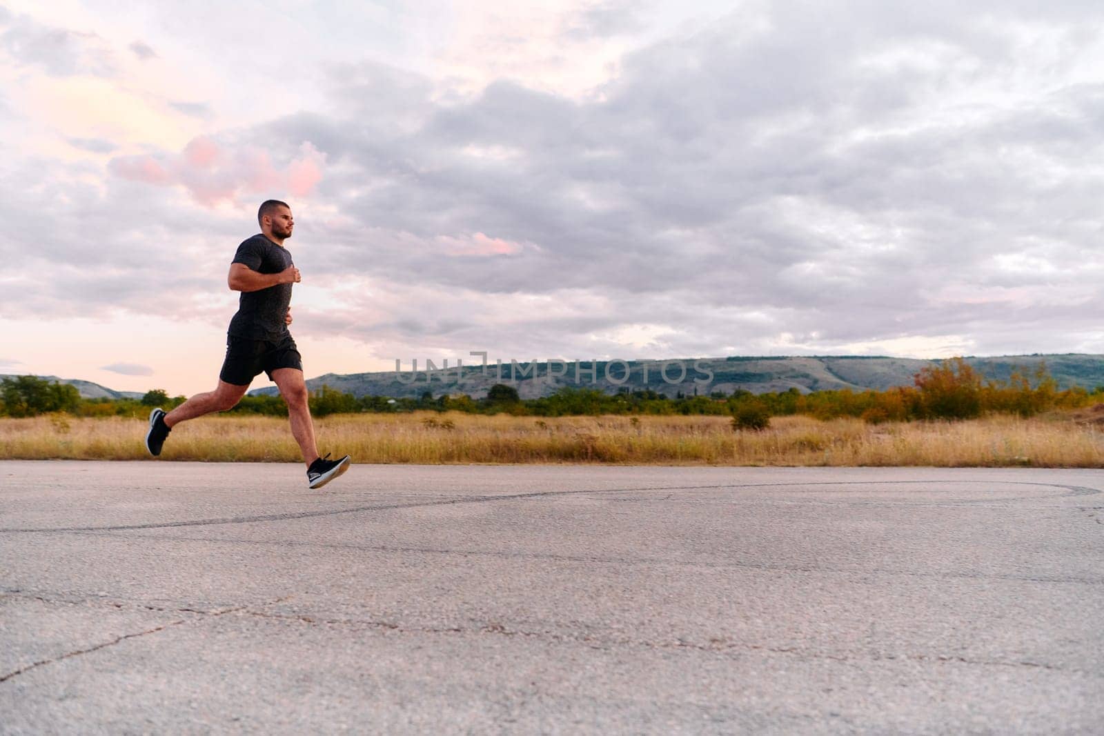 An athletic man jogs under the sun, conditioning his body for life's extreme challenges, exuding determination and strength in his preparation for the journey ahead