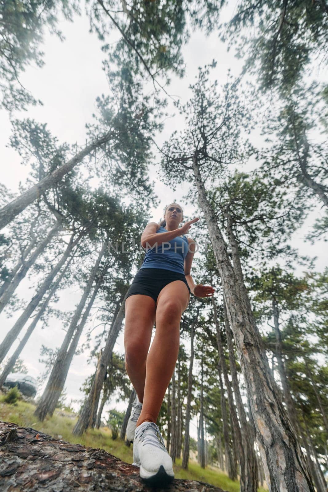 A brave woman traverses through the forest, fearlessly leaping over dangerous obstacles with determination and agility, showcasing her adventurous spirit and athletic prowess.