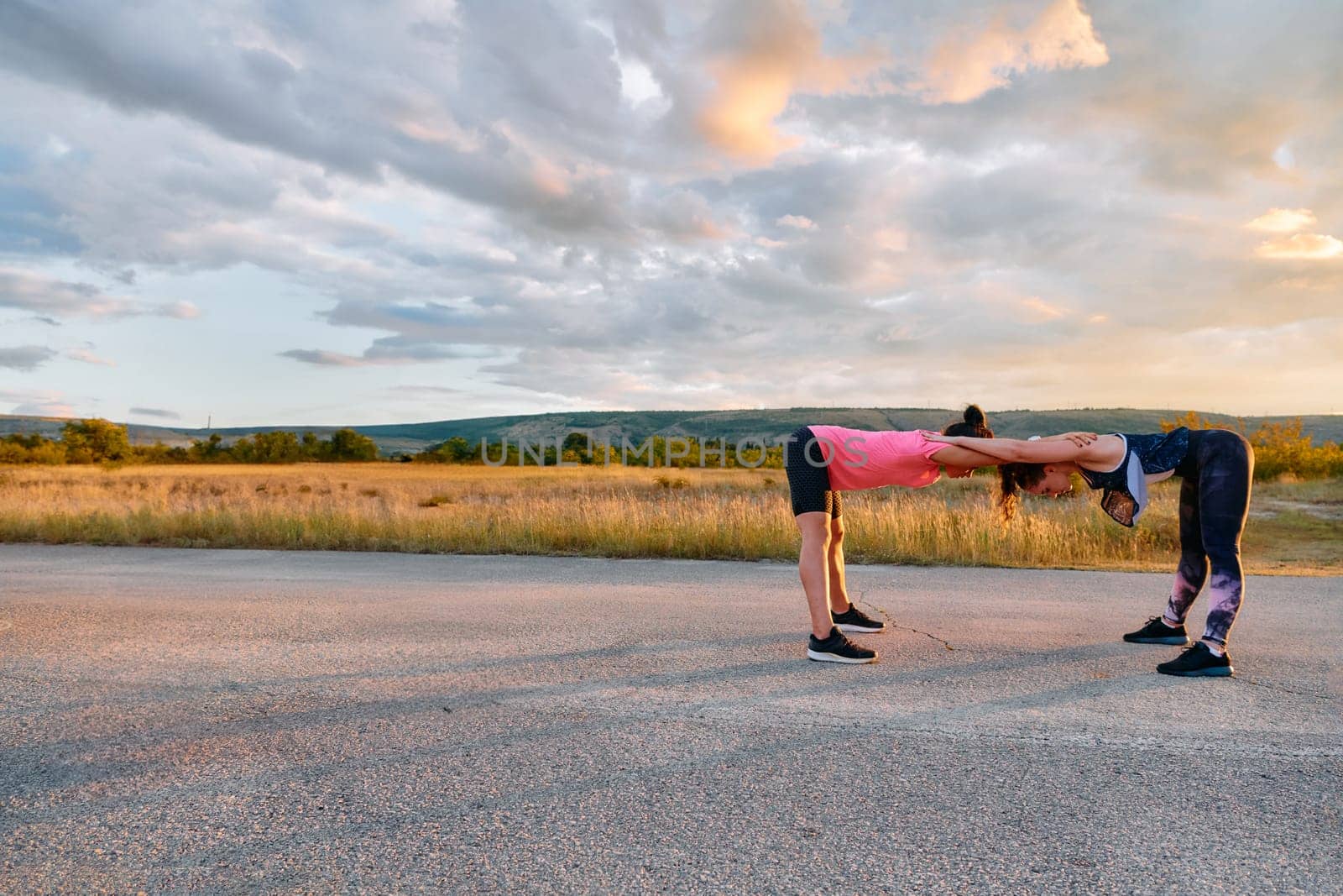 Womens Athletes Stretching at Sunset in Beautiful Natural Surroundings by dotshock
