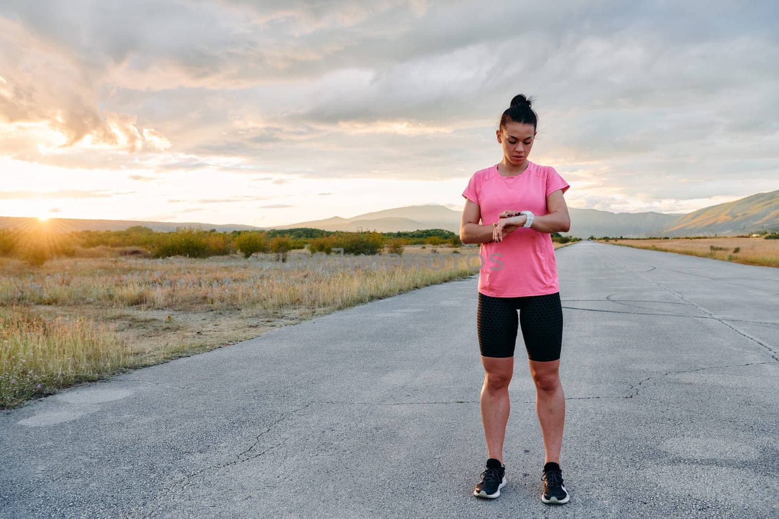 A lone athlete is captured stretching gracefully against the backdrop of a stunning sunset, her silhouette a testament to dedication and resilience after an intense run