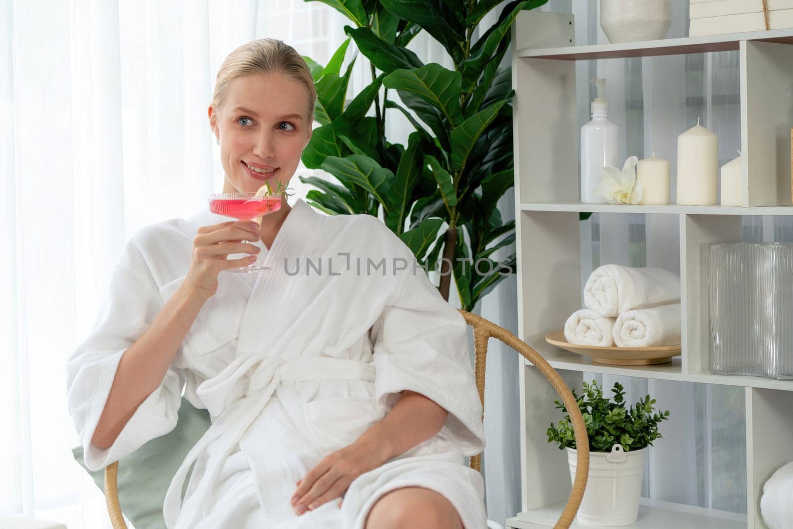 Beauty or body treatment spa salon vacation lifestyle concept with woman wearing bathrobe relaxing with drinks in luxurious hotel spa or resort room. Vacation and leisure relaxation. Quiescent