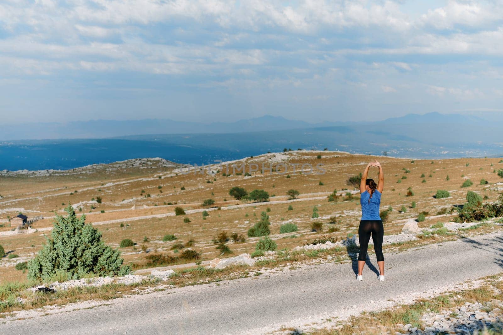 Determined Female Athlete Stretching After an Intense Run Through Rugged Mountain Terrain. by dotshock