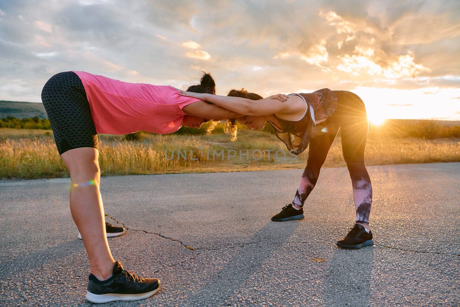 Two women athletes are seen stretching after an intense run, epitomizing dedication to fitness and appreciation for nature's beauty.