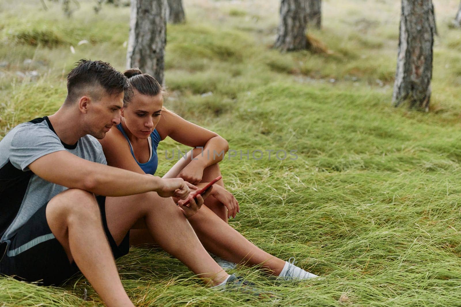 Romantic Couple Planning New Running Routes in the Forest with Smartphone by dotshock