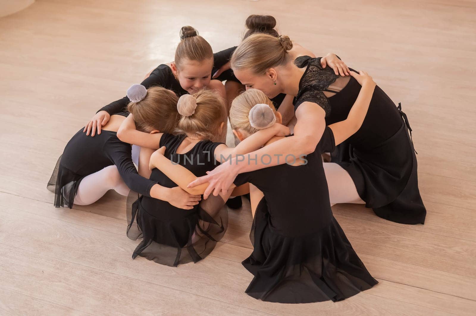 Five little ballerinas and a teacher are sitting in a circle hugging. by mrwed54